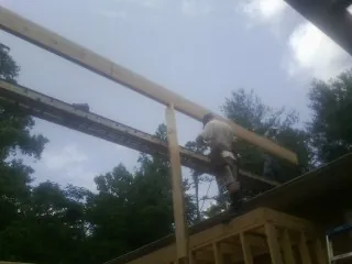Carpenter setting a ridge beam over a new addition frame — Ice Dam Removal by Roofing Brothers in Una