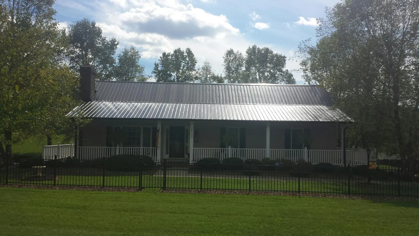 Gray metal roof on a brick ranch with a full width front porch — Gutter Guard Installation work by our crew in Una