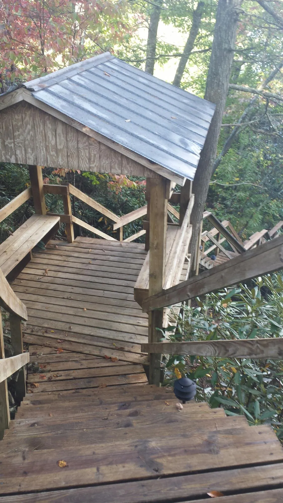 Metal roofed shelter over wooden steps on a wooded walkway — Skylight Repair & Installation work by our crew in Una